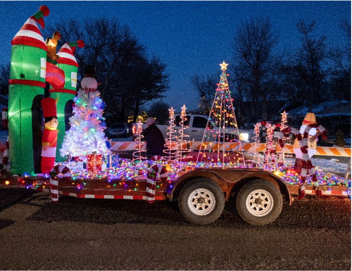 A Christmas parade float with Christmas trees and an inflatable snowman, nutcracker, and building at the Gillette Main Street Parade of Lights.